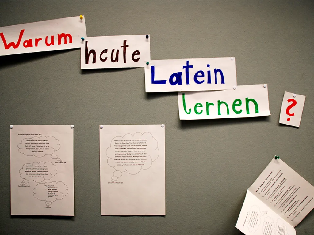 Ein Wandbild aus bunten Buchstaben fragt „Warum heute Latein lernen?“.